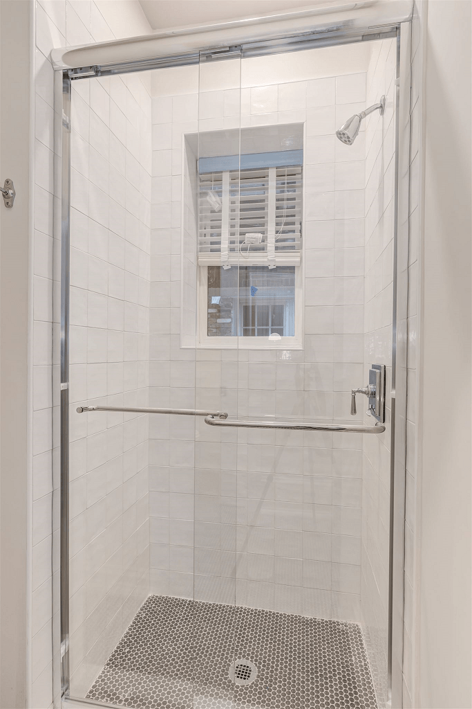 a white tiled bathroom with a glass shower door
